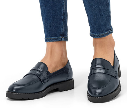 Beine einer Person in Jeans und Leder-Loafern.