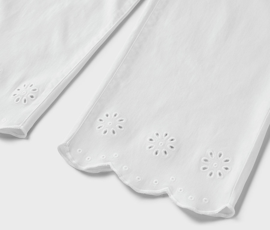 Detailansicht einer weißen Jeans mit Lochstickerei am Saum.