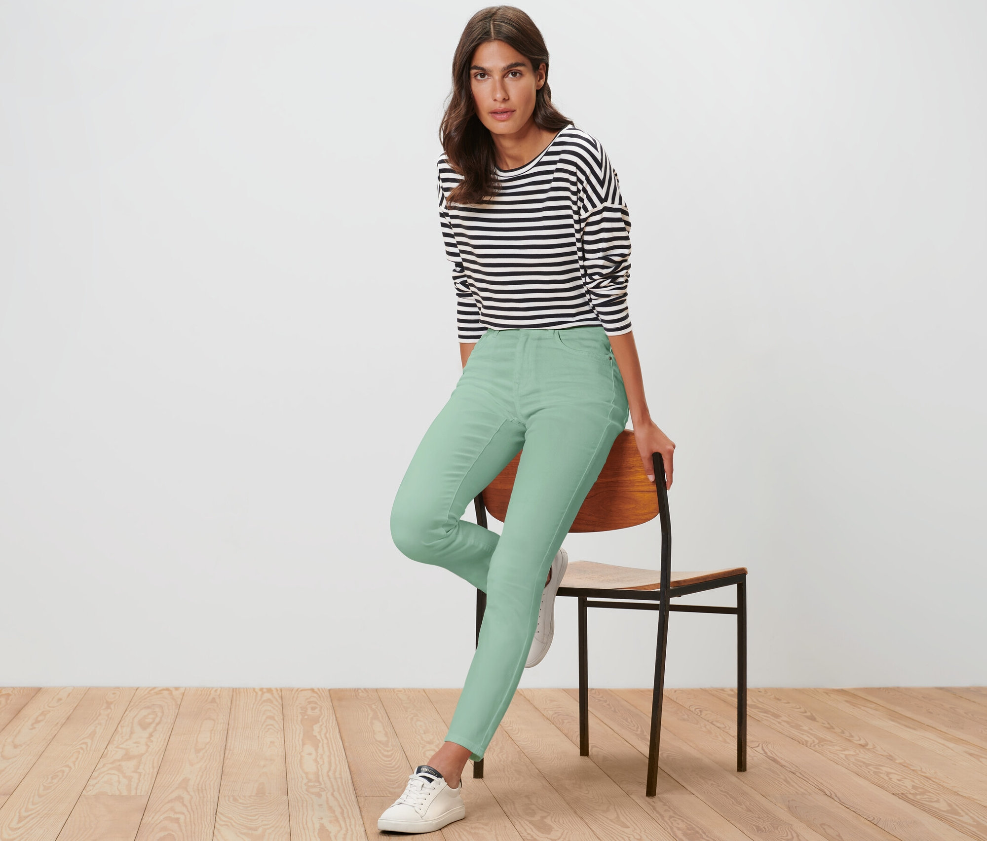 Eine Frau sitzt auf einem Stuhl und trägt eine hellgrüne Colored Jeans ‒ Fit »Emma«.