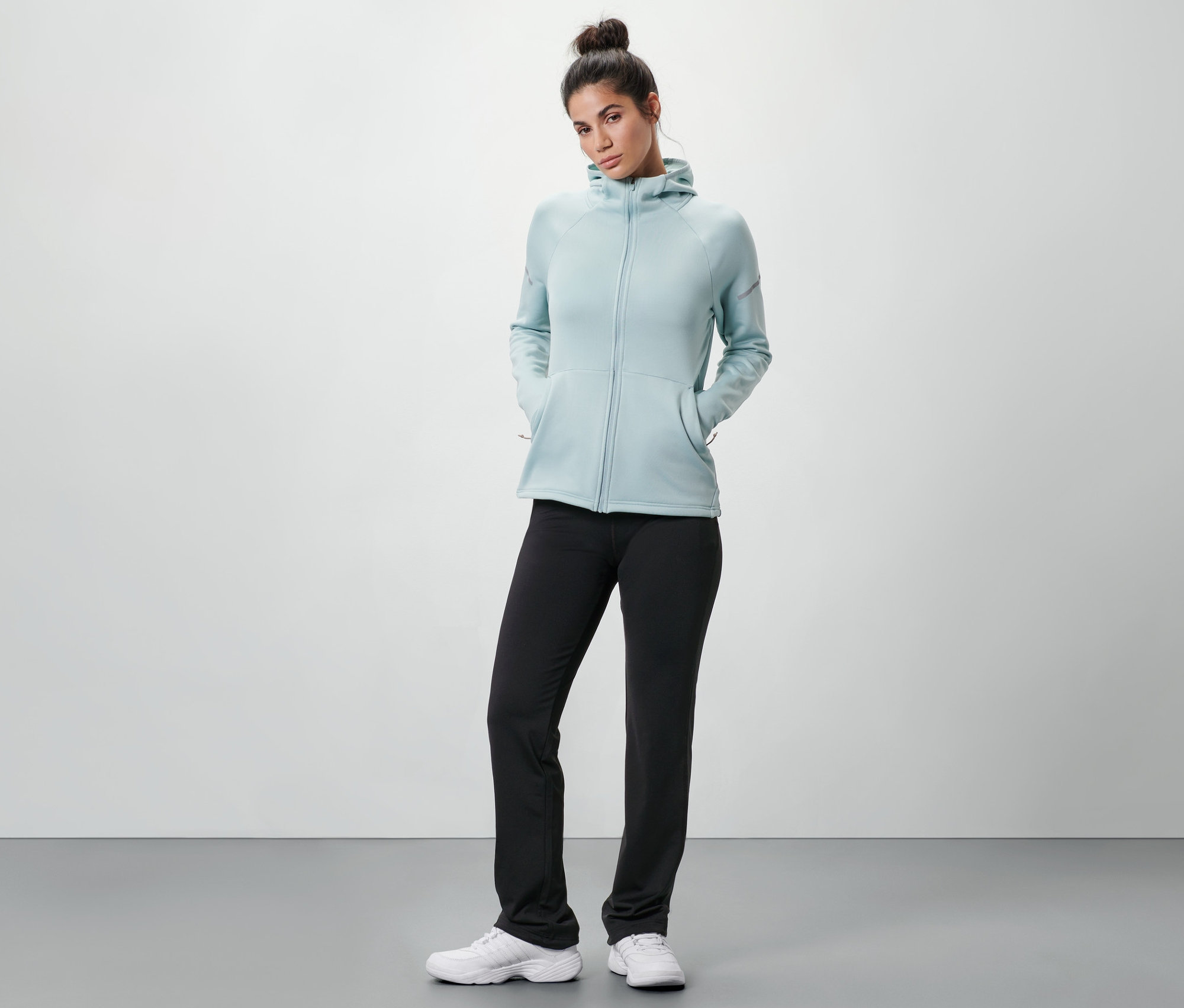 Frau trägt eine Thermohose, eine Kapuzenjacke und Turnschuhe.