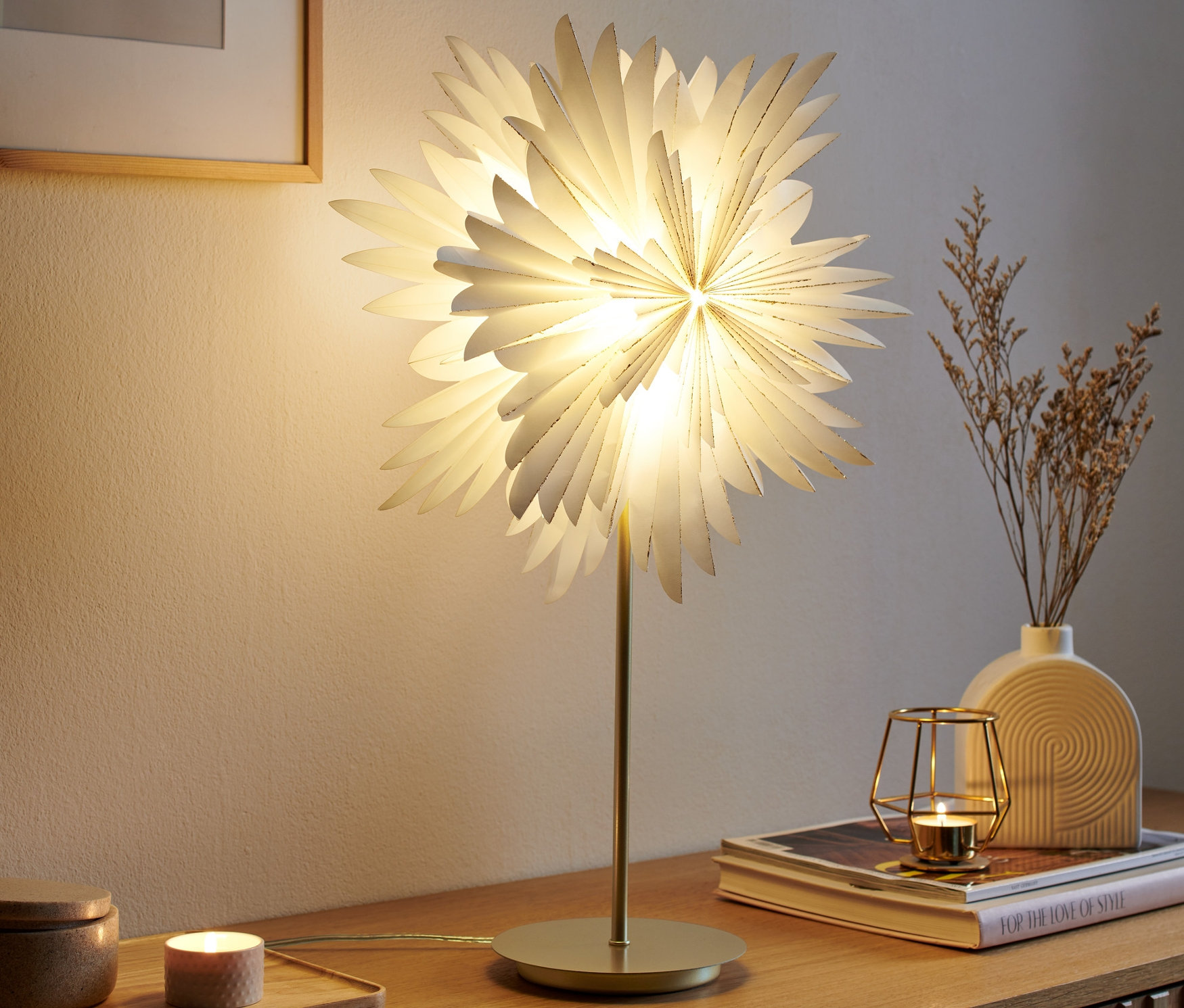 Eine leuchtende LED-Dekoleuchte »Stern« steht auf einer Holzkommode.