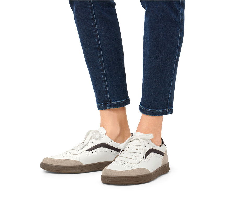 Beine in Jeans und Leder-Sneaker.