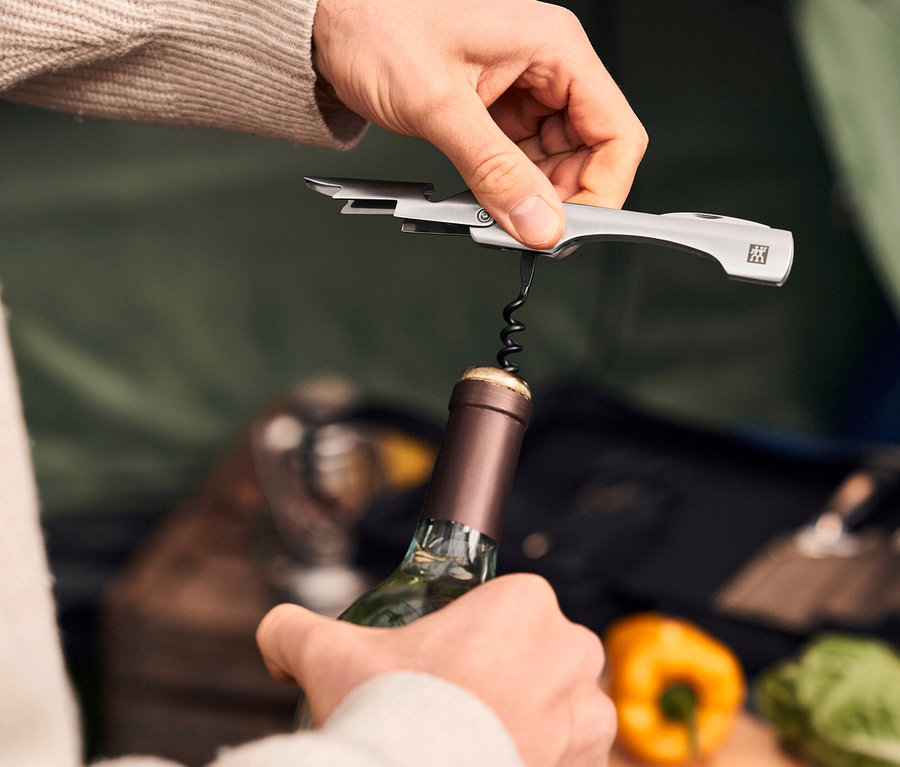 Eine Person öffnet eine Weinflasche mit einem ZWILLING Messer-Traveller-Set.