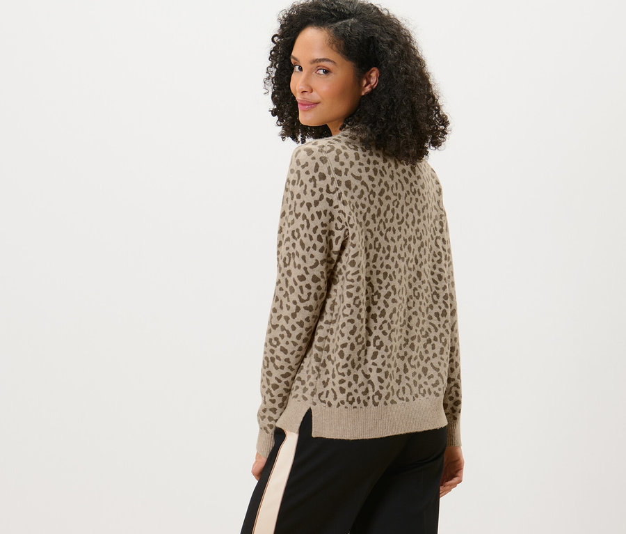 Frau blickt über die Schulter und trägt einen bedruckten Strickpullover.