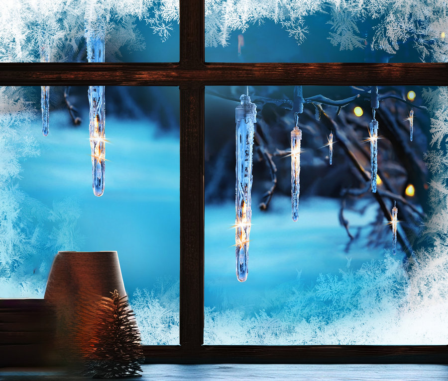 Ein frostiges Fenster mit Blick auf eine verschneite Landschaft und AMARE LED-Lichterkette »Eiszapfen«.