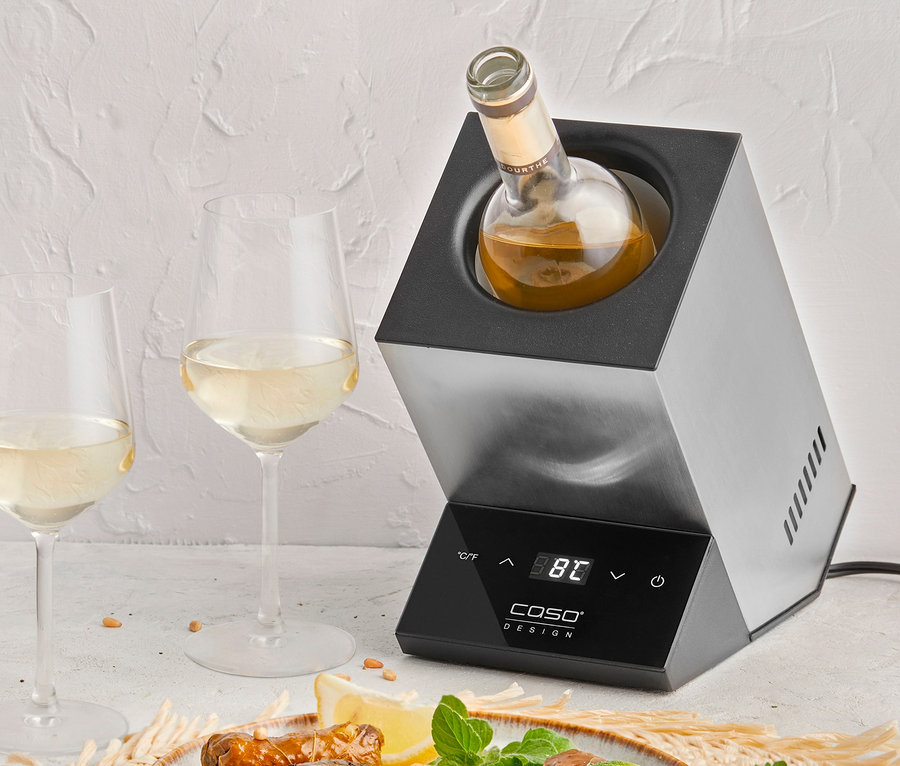 Wein im CASO Weinkühler Wine Case One neben zwei Gläsern Wein und einem Teller gefüllter Blätter.