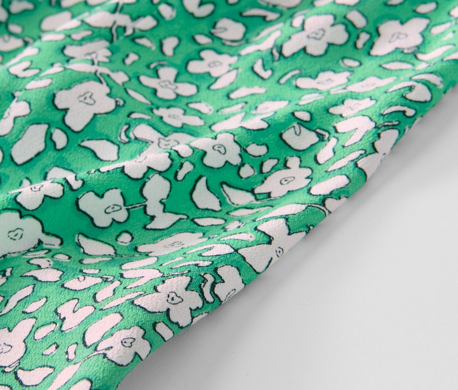 Detailansicht eines grünen, bedruckten Midirocks.