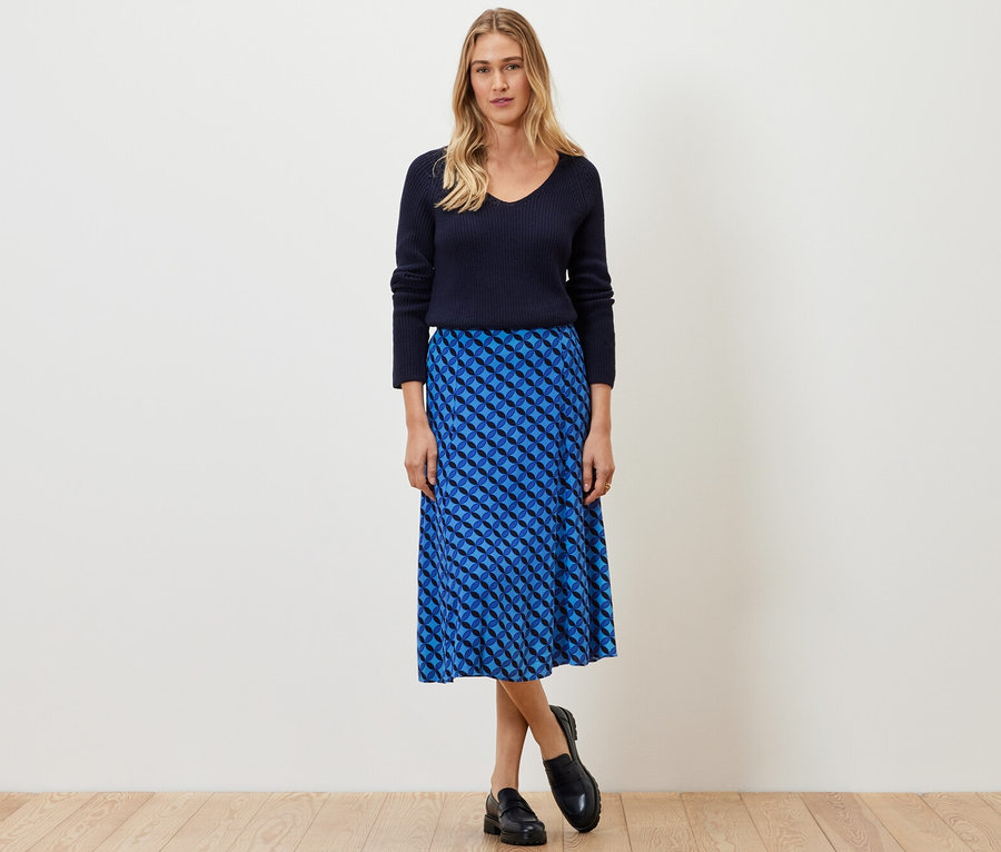 Frau posiert in marineblauem Pullover und bedrucktem Midirock.