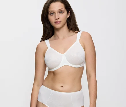 Frau trägt einen vanillefarbenen Triumph Essential »Minimizer W X« BH und passende weiße Slips, blickt nach vorne.