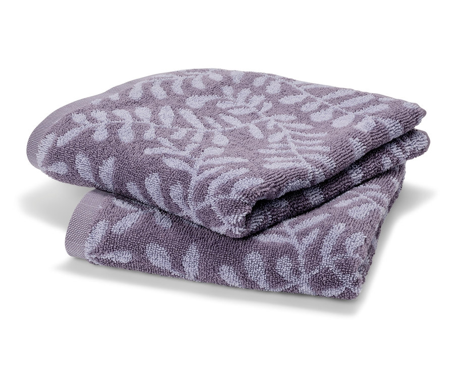 Zwei lilafarbene Frotteehandtücher liegen gefaltet übereinander. Die Handtücher haben ein zartes Blattmuster.