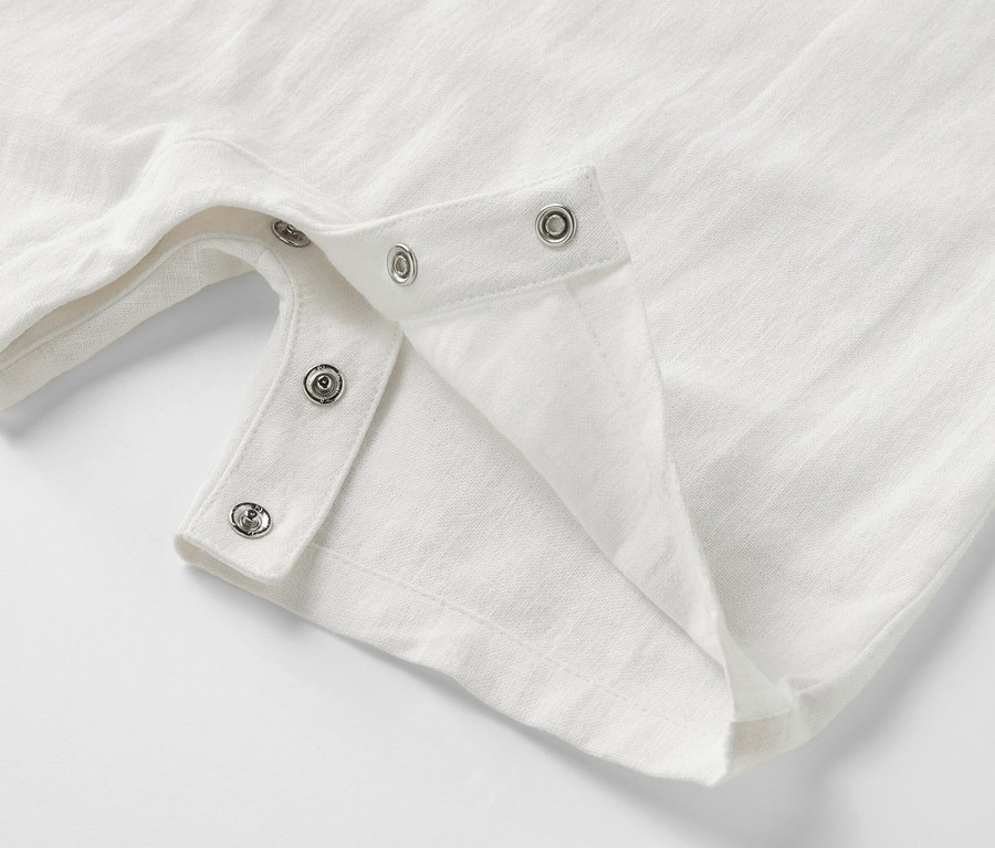 Detailansicht eines weißen Baby-Matrosen-Stramplers mit Druckknöpfen.