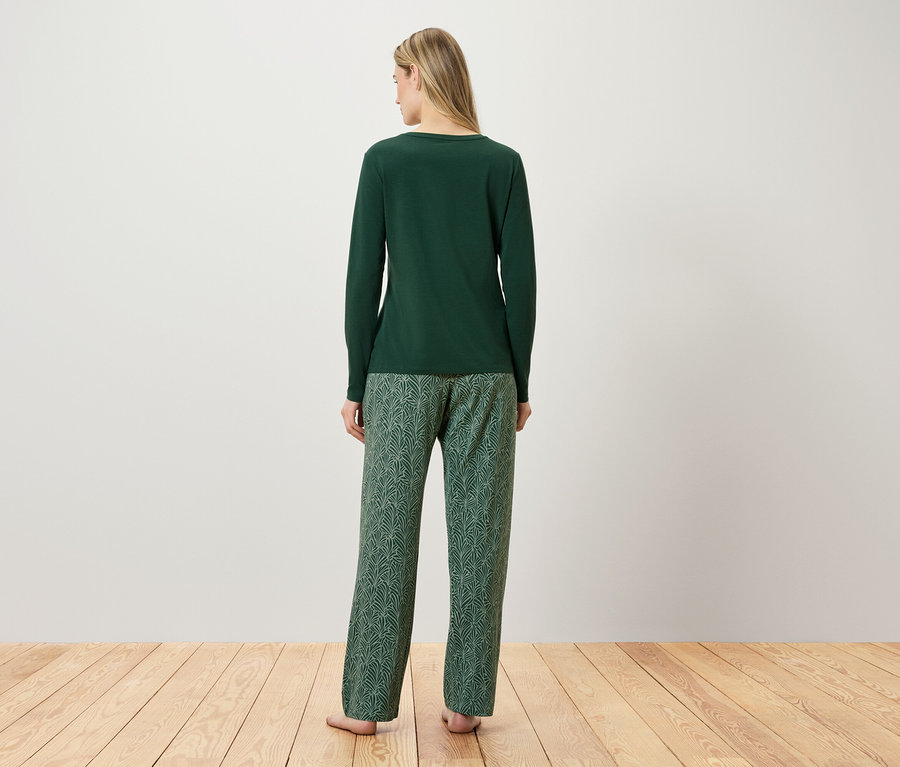 Frau steht mit dem Rücken zur Kamera und trägt einen grünen Schlafanzug.