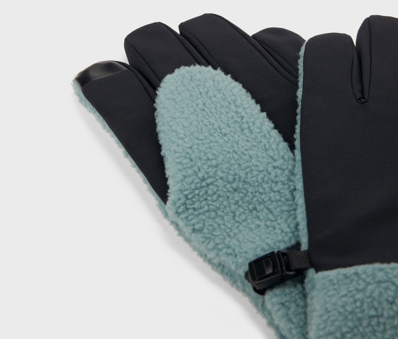 Detailaufnahme von blaugrünen und schwarzen Handschuhen mit Fleecefutter und schwarzer Schnalle.