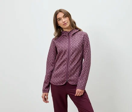 Frau posiert in einem burgunderfarbenen Kapuzenpullover und einer Hose.