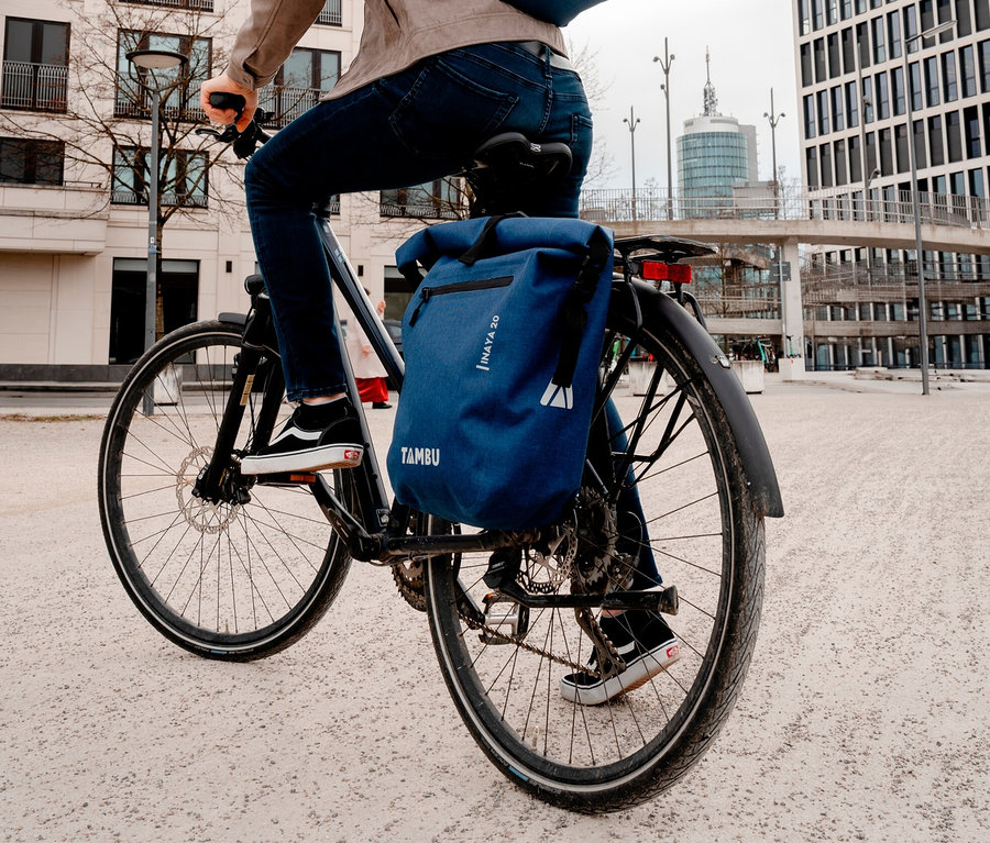 Mann fährt Fahrrad mit blauer Tambu INAYA Fahrradtasche.