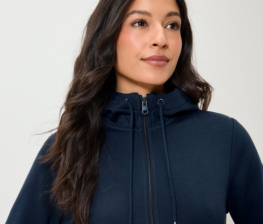 Eine Frau trägt einen marineblauen Kapuzenpullover mit Reißverschluss.