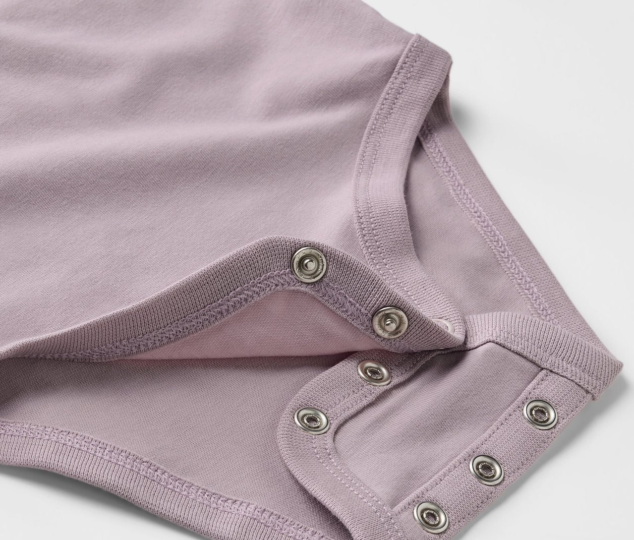 Detailansicht eines lila Baby-Bodys mit Mitwachsfunktion und Druckknöpfen.