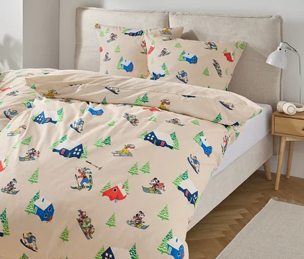 Bettwäsche mit Ski- und Baumdruck auf einem Bett.
