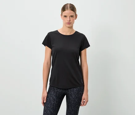 Frau steht und trägt ein schwarzes T-Shirt und gemusterte Leggings.