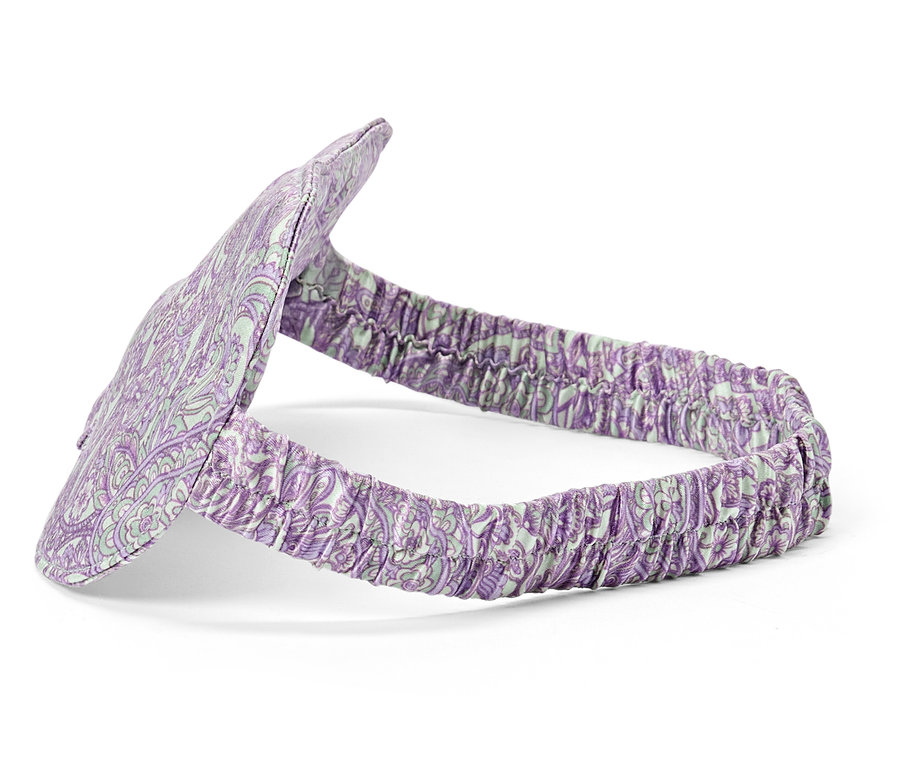Nahaufnahme einer lila gemusterten Schlafmaske mit Gummiband auf weißem Hintergrund.