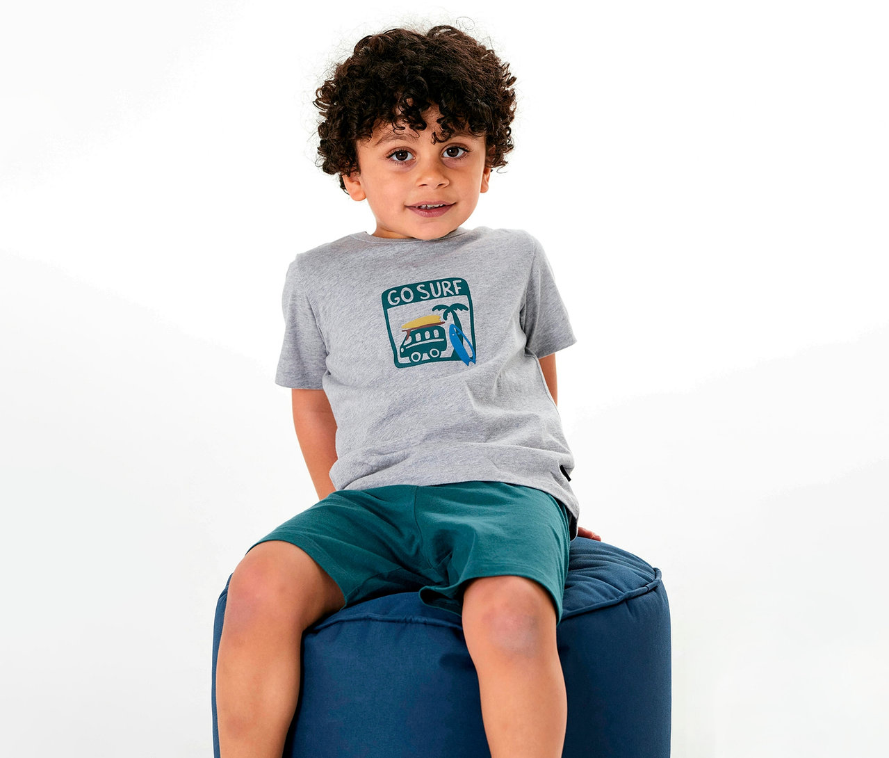 Junge sitzt auf einem Hocker und trägt einen kurzen SCHIESSER Kinder-Pyjama.