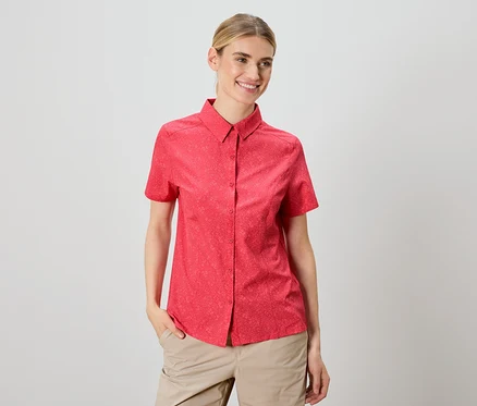 Frau trägt ein rotes kurzärmeliges Hemd und beige Hosen.
