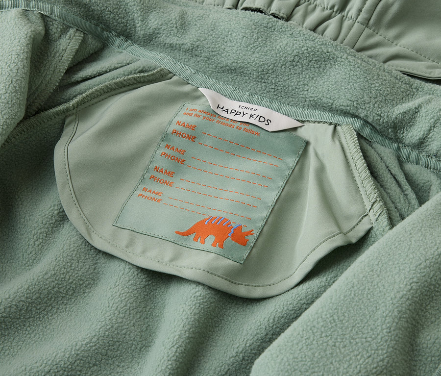 Innenansicht einer hellgrünen Tchibo Happy Kids Jacke mit Namensschild und Triceratops-Motiv.