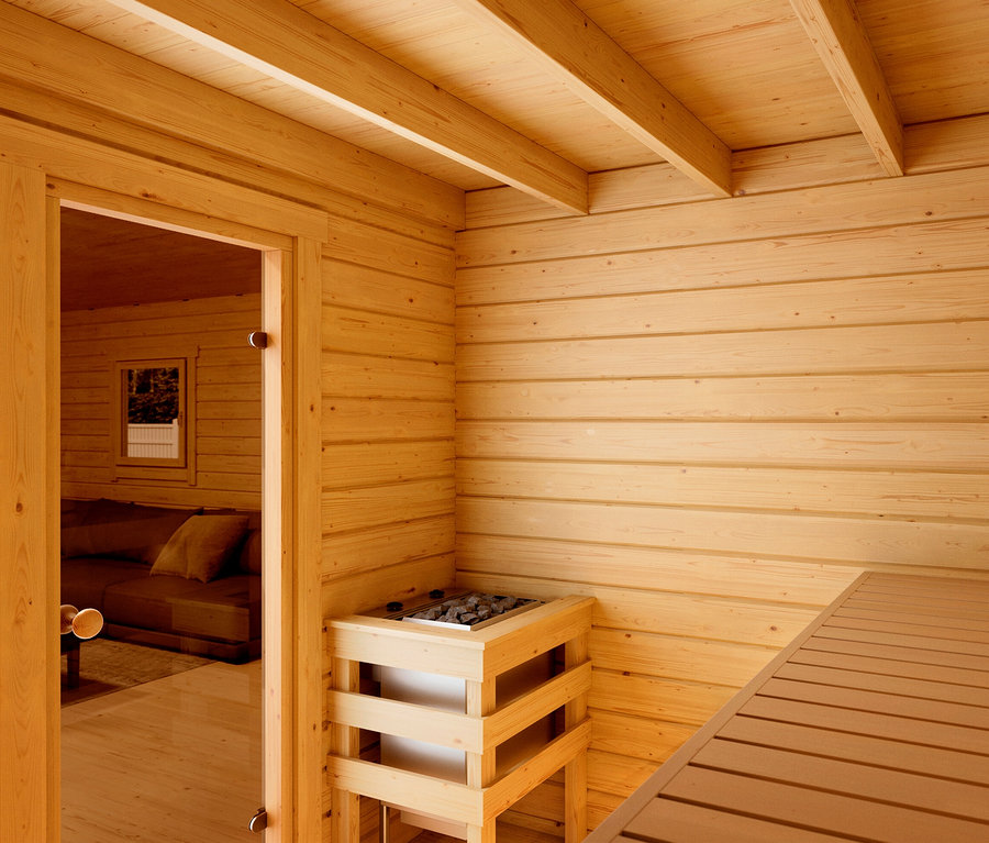 Innenaufnahme einer Sauna mit Holzofen, Holzwänden und einer Sitzbank.