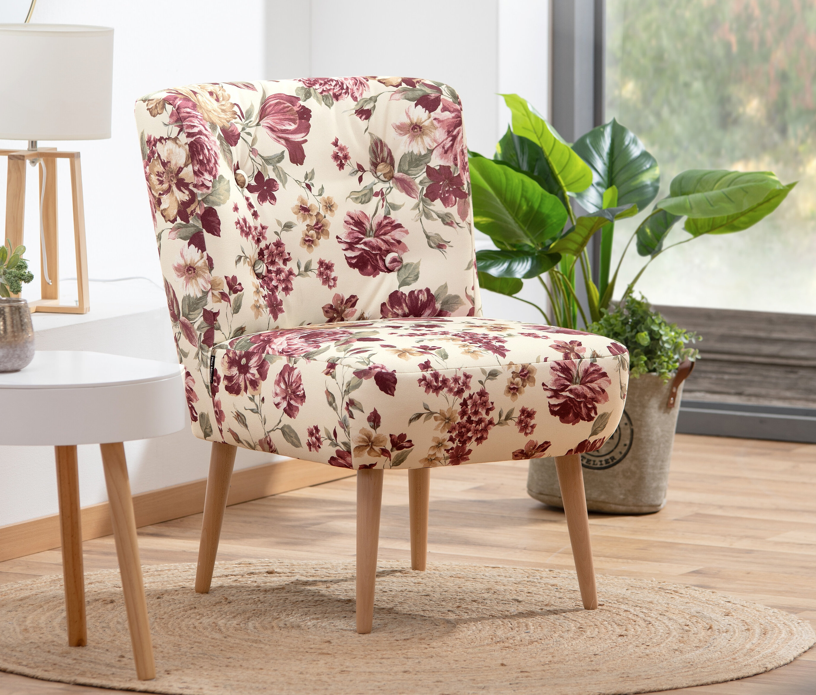 Cocktail-Sessel »Fiona« mit floralem, beige Bezug steht auf einem Teppich.