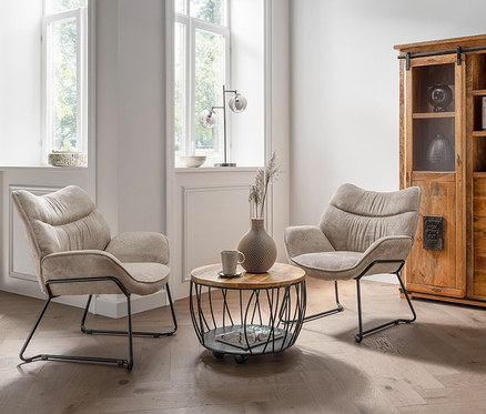 Zwei beige DeVries Sessel »Aliano« stehen im Wohnzimmer auf einem Holzboden.