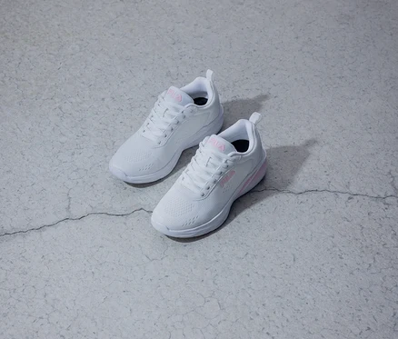 Zwei weiße Fila-Sneaker mit pinkfarbenem Logo liegen auf einem grauen Untergrund.