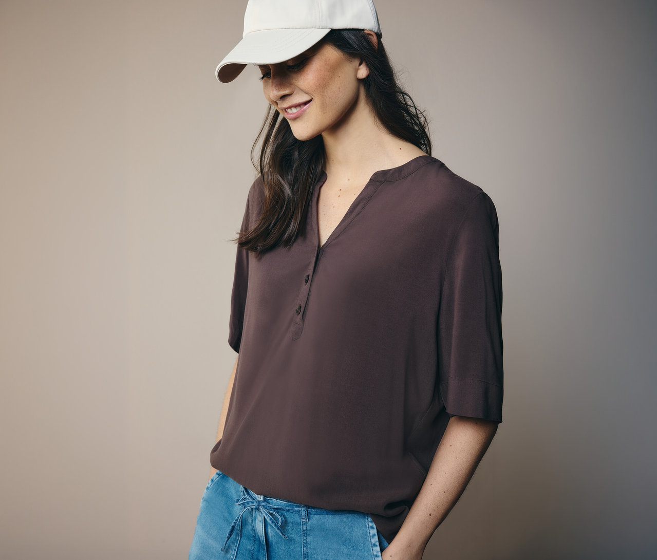 Frau mit weißer Kappe und brauner CECIL Tunikabluse.