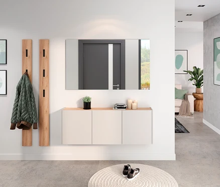 Flur mit Spiegel über einem weißen Schrank mit Holzplatte, Garderobenpaneel mit Jacke und rundem Teppich mit Schuhen.