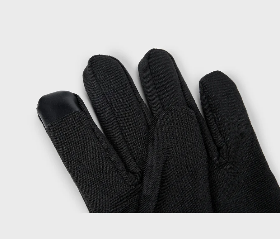Nahaufnahme eines schwarzen Handschuhs, der die Finger zeigt, mit einem schwarzen, touchscreen-kompatiblen Aufnäher an der Zeigefingerspitze.