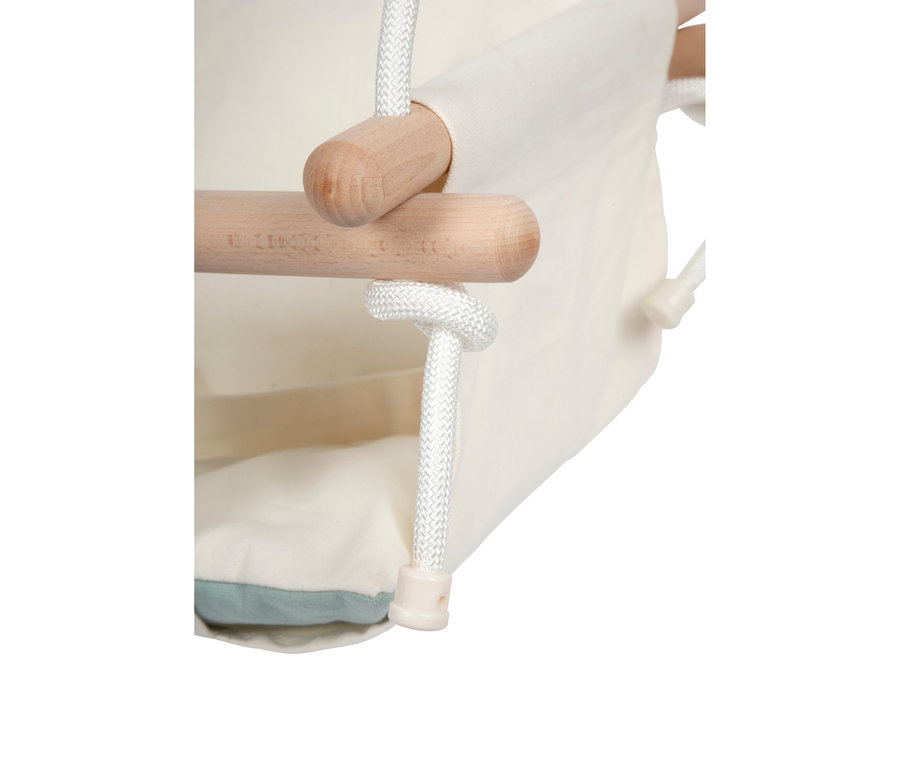 Nahaufnahme der small foot Babyschaukel Komfort, die den cremefarbenen Stoffbezug, helle Holzstangen und weiße geflochtene Seile zeigt. Ein hellblaues Kissen ist am Boden des Sitzes sichtbar.