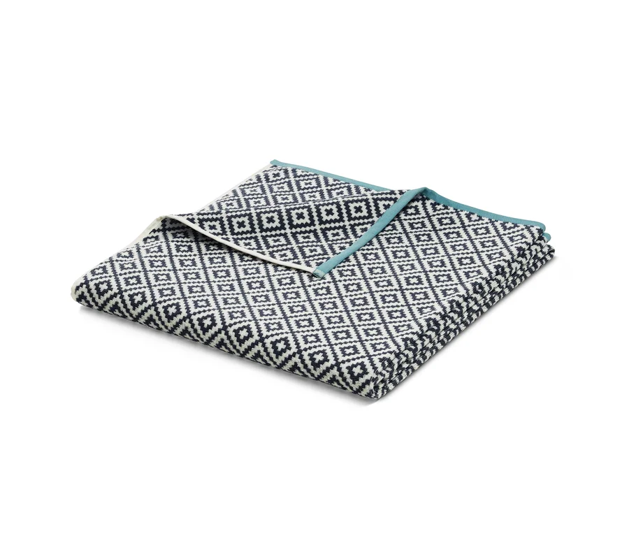 Gefaltetes XL-Frottier-Badetuch, ca. 200 x 100 cm, mit schwarz-weißem geometrischen Muster und hellblauer Bordüre.