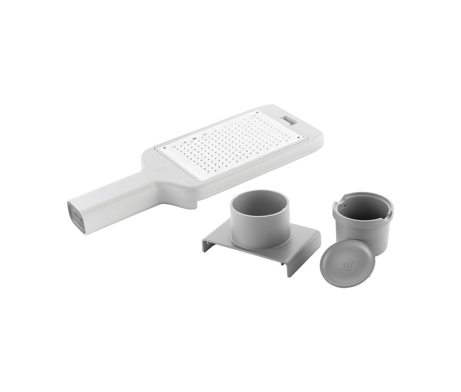 Eine graue und weiße ZWILLING Z-Cut Multireibe mit Griff und rechteckiger Reibefläche, daneben graues Zubehör: eine Basis, ein kleiner Behälter und ein Deckel.