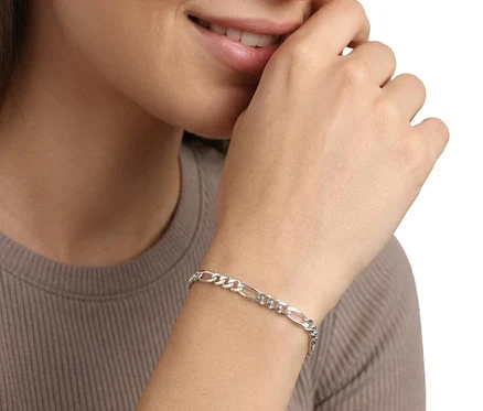 Lächelnde Frau mit einem Amor 925 Silber Figaro Armband am linken Handgelenk, die rechte Hand am Mund.