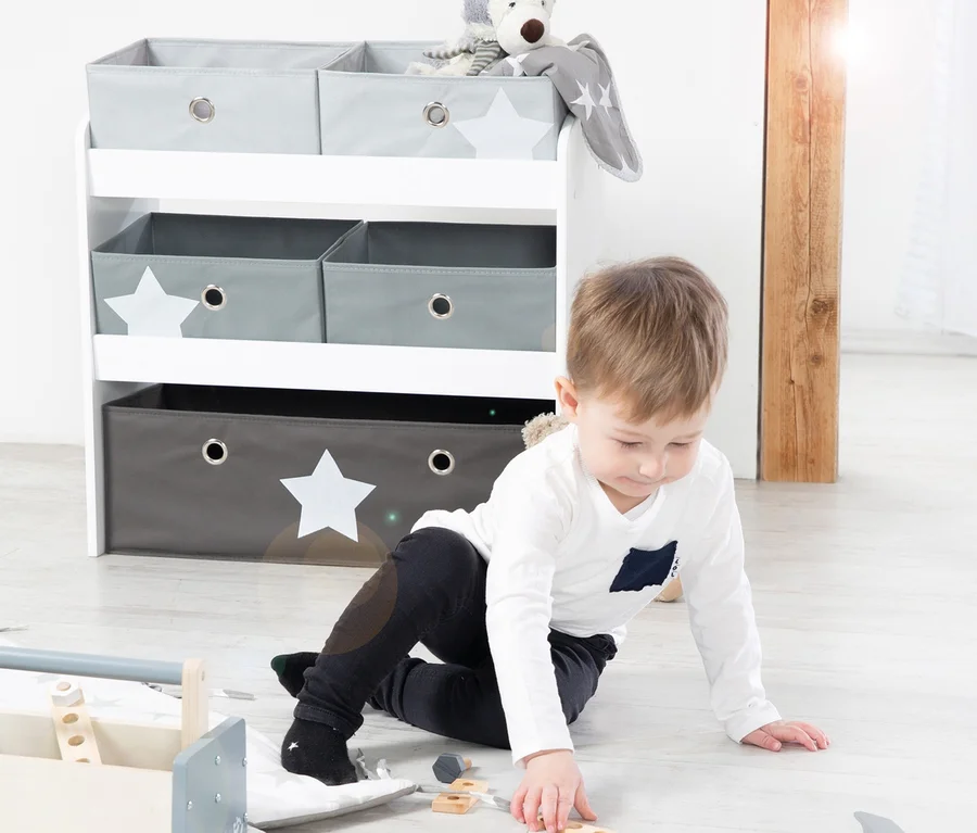 Junge spielt mit Holzspielzeug auf dem Boden neben roba Spielregal "Stars".