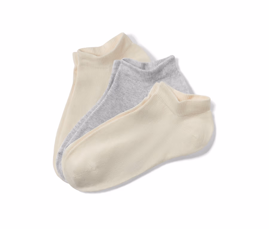 Nahaufnahme von drei Paar Kinder-Sneakersocken in Beige und Hellgrau.