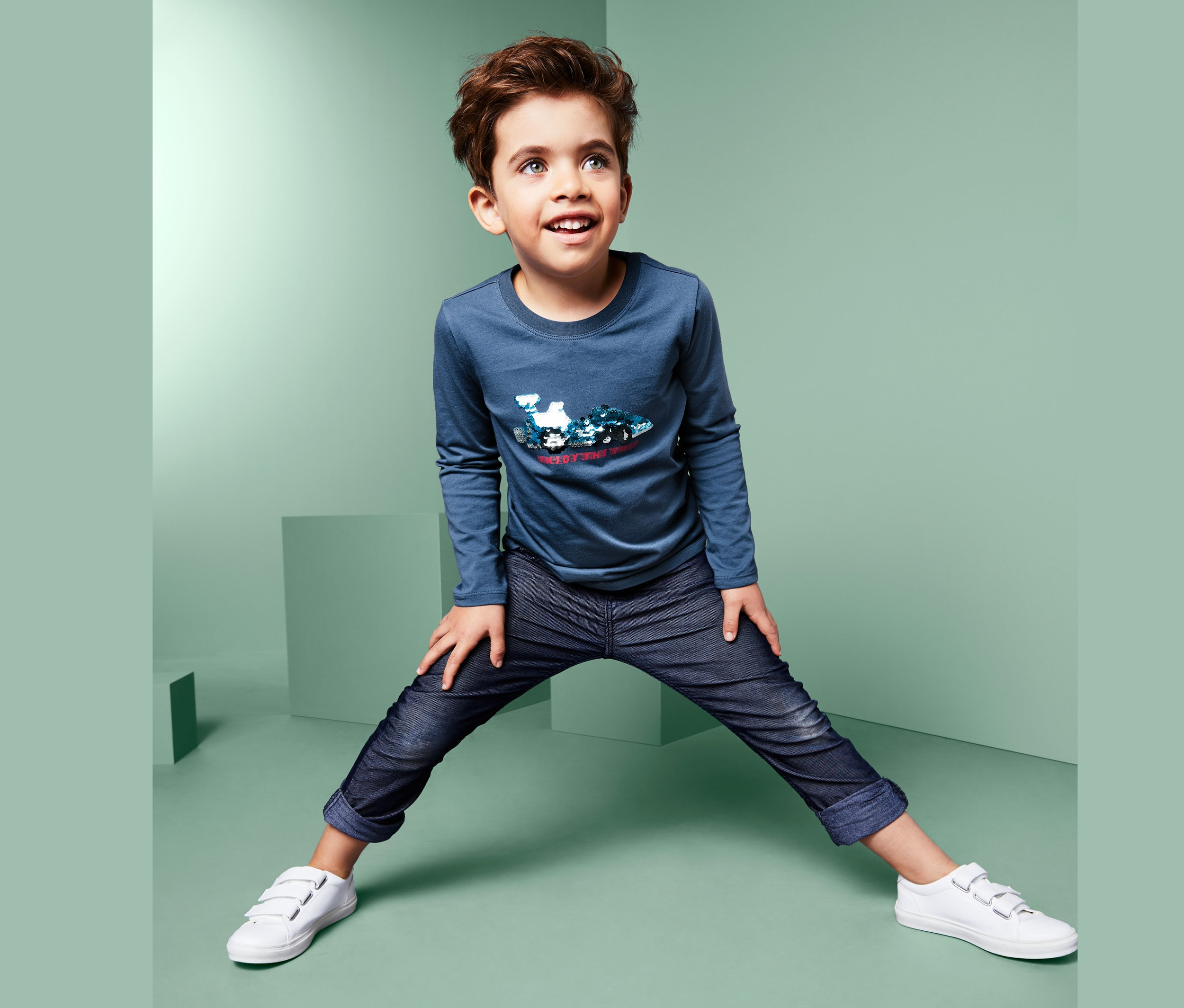 Junge posiert in Langarmshirt mit Wendepailletten.