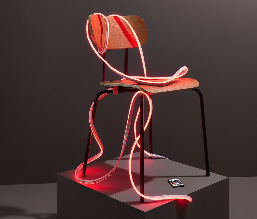 Ein roter LED-Leuchtschlauch mit Lichteffekten ist um einen Stuhl gewickelt.