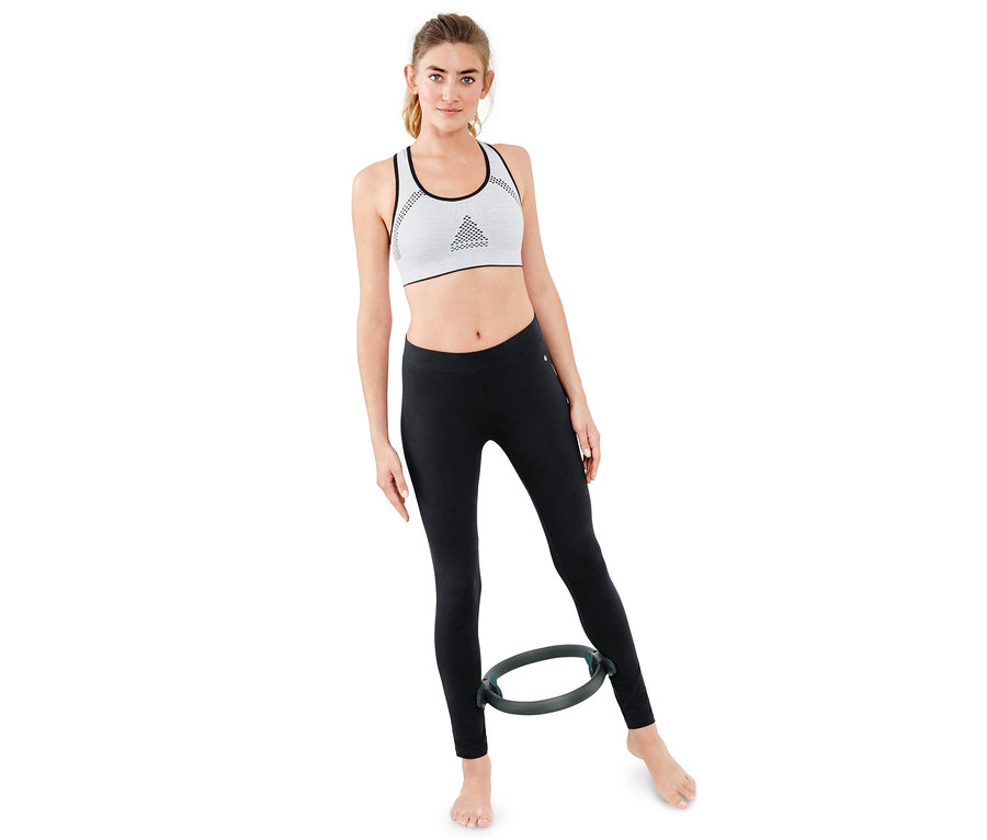 Frau trainiert mit Pilatesring zwischen den Beinen.