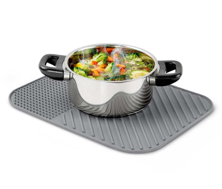 Ein Kochtopf aus Edelstahl, gefüllt mit Gemüsesuppe, steht auf einer Geschirr-Abtropfmatte aus Silikon.
