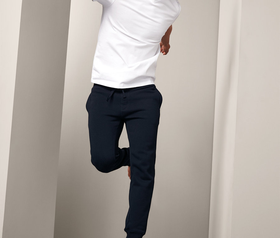 Mann mit weißem T-Shirt und Sweathose springt.