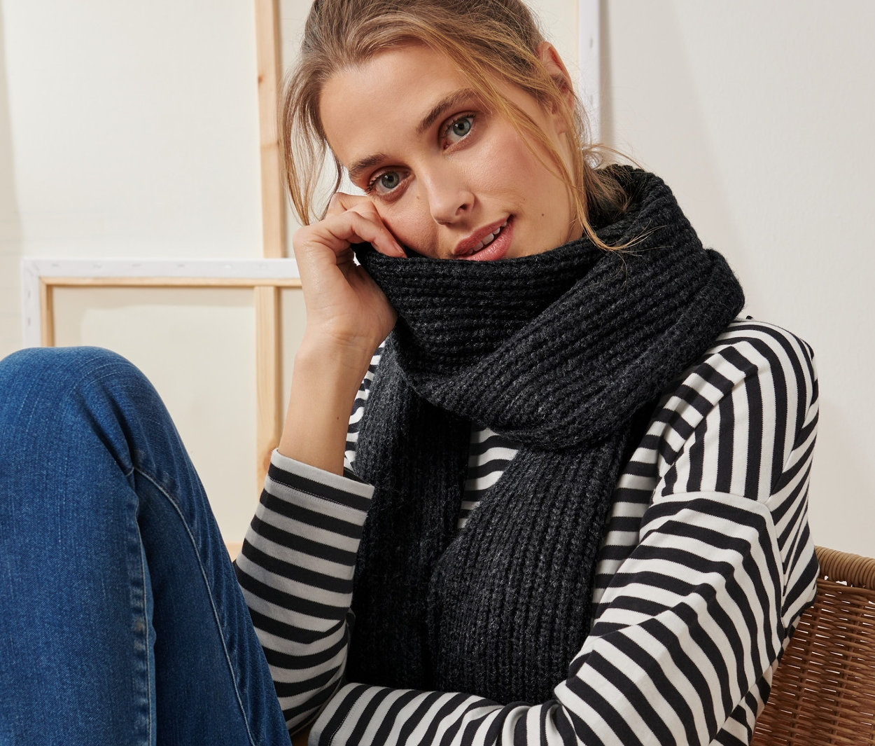 Frau sitzt auf einem Stuhl und trägt einen anthrazitfarbenen Strickschal.