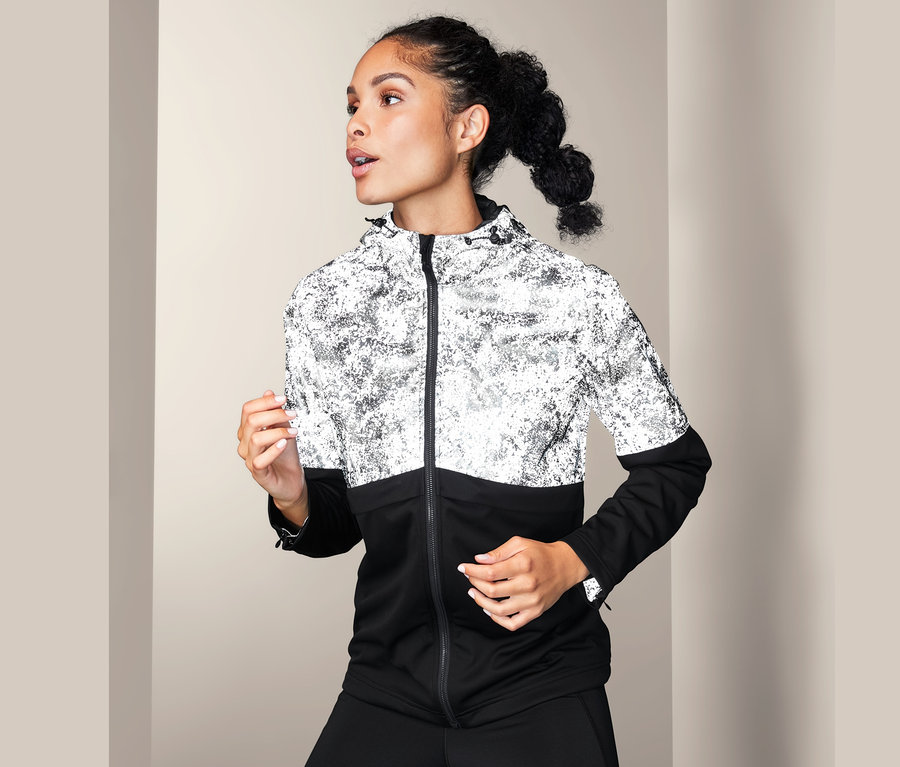 Frau trägt eine Softshelljacke mit dekorativen Reflektivelementen.