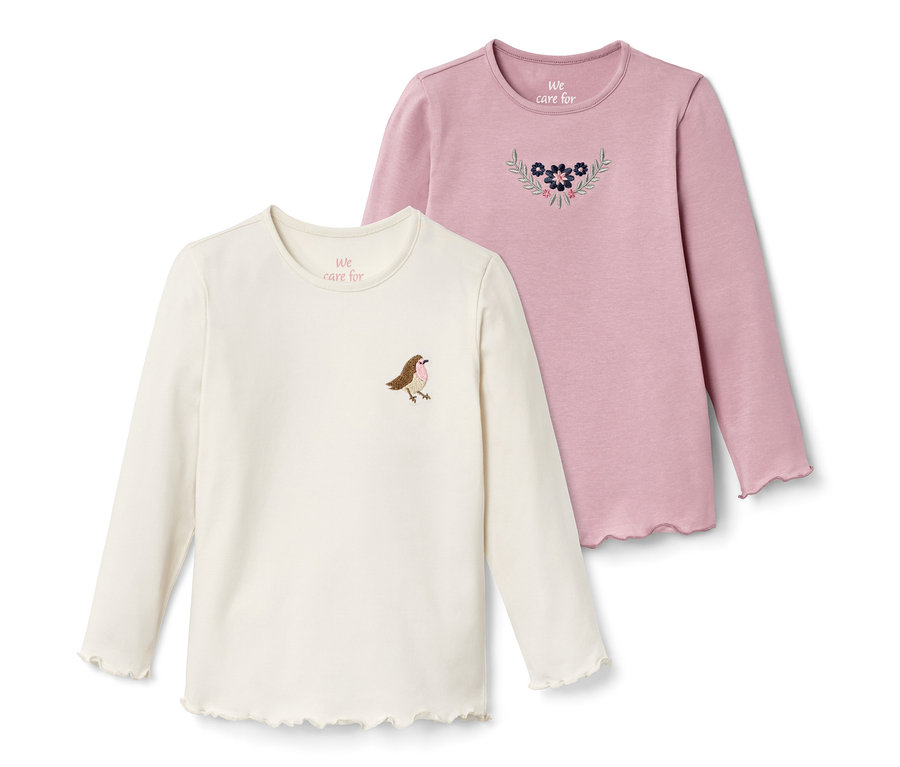 Zwei Langarmshirts: ein cremefarbenes Shirt mit Vogel und ein rosafarbenes Shirt mit Blumen.
