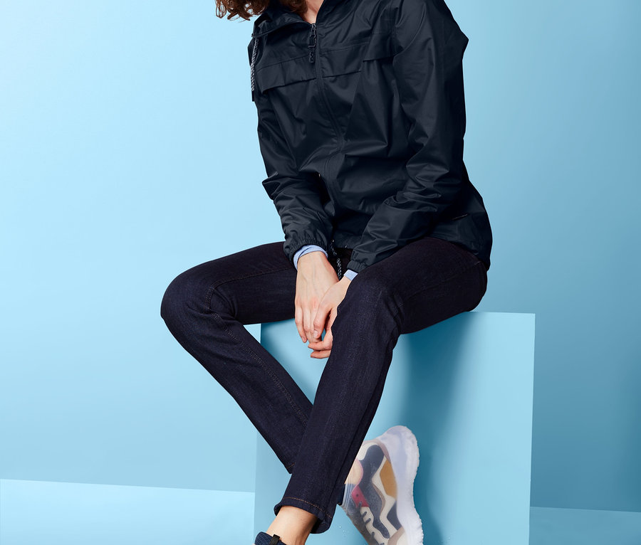 Frau sitzt auf blauem Block und trägt Regen-Überziehschuhe.