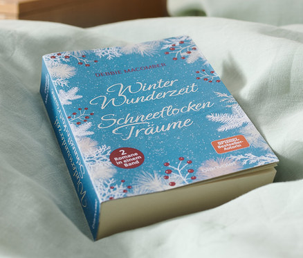 Doppelroman »Winterwunderzeit« und »Schneeflockenträume« liegt auf einem Bett.